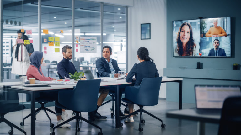 Businesspeople do Video Conference Call with Big Wall TV in Office Meeting Room. Diverse Team of Creative Entrepreneurs at Big Table have Discussion